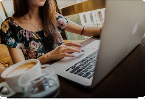 Vrouw combineert werk met zelfzorg door bewust pauzes te nemen met een kop koffie, terwijl ze achter haar laptop werkt